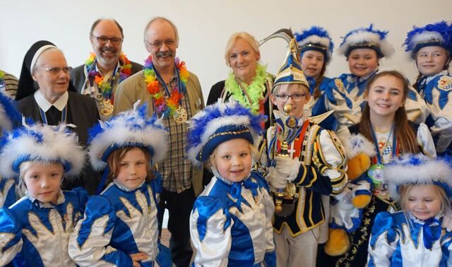 Viele Kinder in Karnevalsoutfit mit einigen weiteren Erwachsenen hinter ihnen.