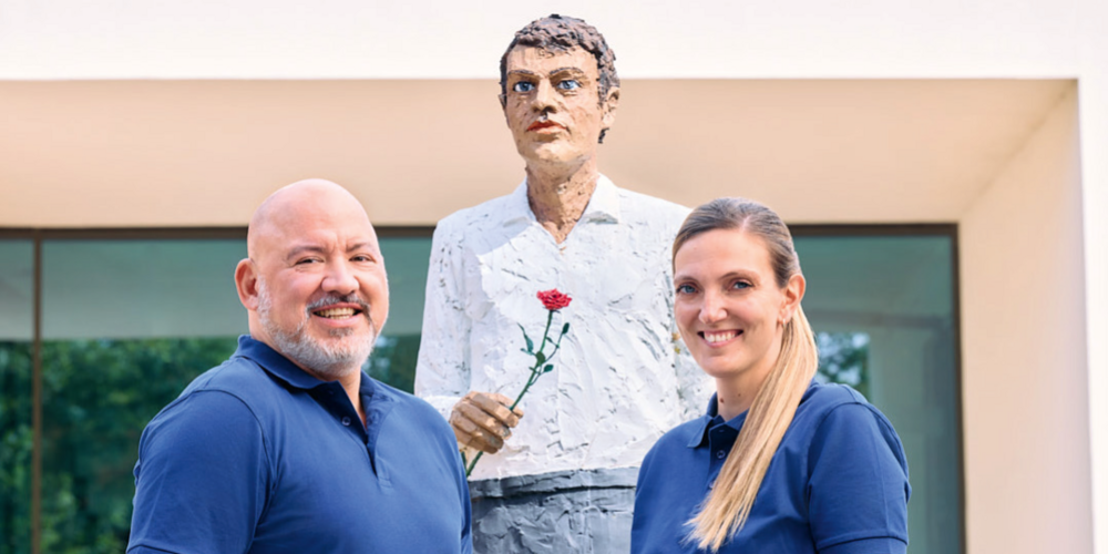 Porträtaufnahme der Podcaster Ingo und Sabine vor dem Mann mit Rose